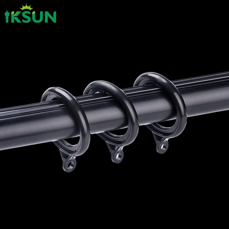 Close-up detail of black aluminum curtain rod with black hooks on a black background, convenient for hanging curtains.